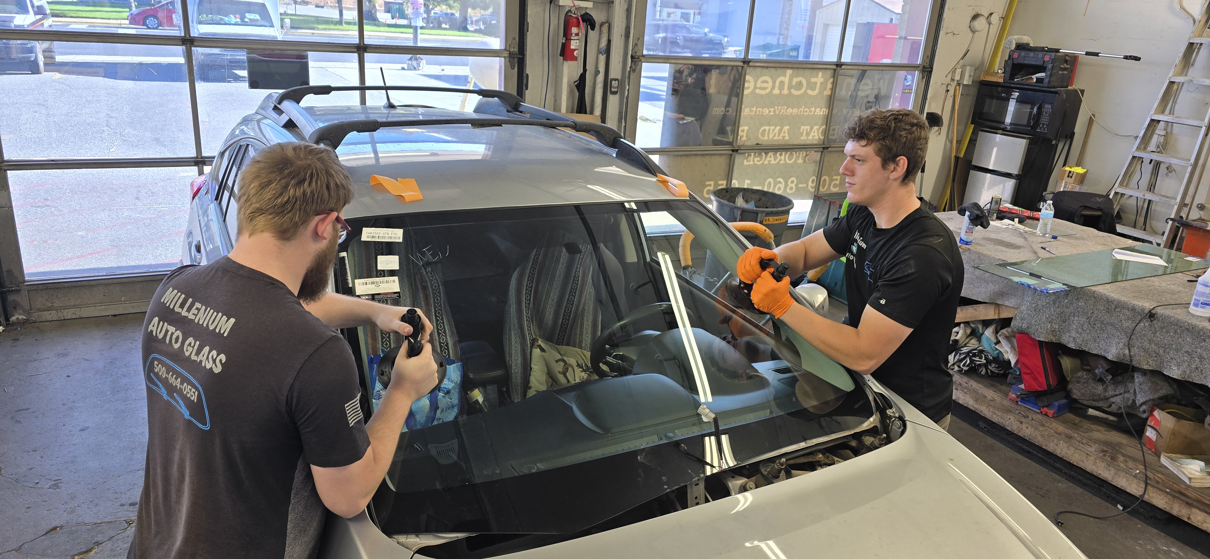 Millenium technicians setting a new windshield on an SUV
